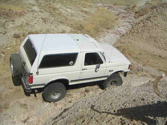 White 1988 Ford Bronco with camper shell on a dirt road