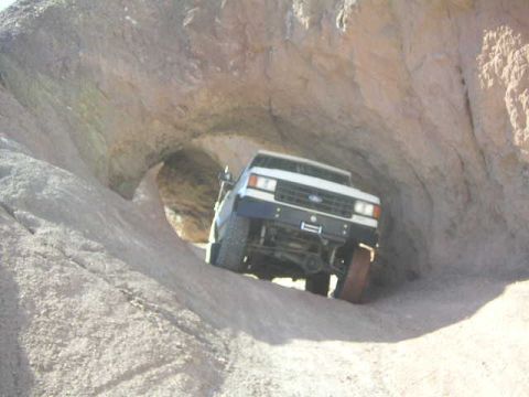 1988 Ford Bronco - A white Ford Bronco navigates a narrow passage through rock formations.