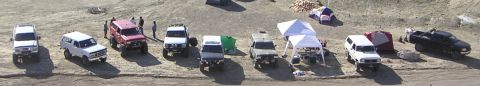 1988 Ford Bronco - Multiple off-road vehicles and camping equipment are set up in an outdoor location.