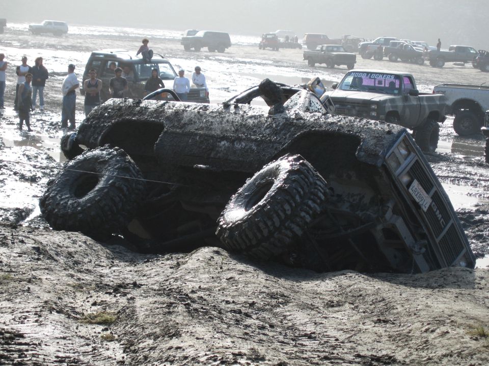 Overturned mud-covered truck with visible license plate LRX9912 and GMC badging
