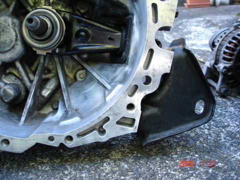1993 Mazda MX-3 - Close-up view of a transmission bell housing and an alternator, likely for a vehicle engine.