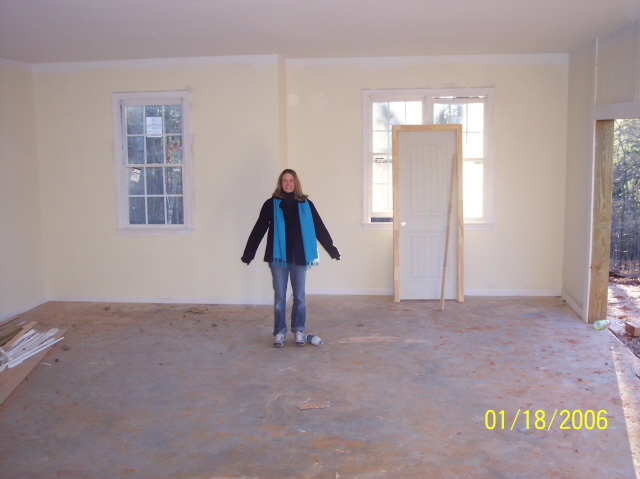 Interior scene with a person standing in an unfinished room with windows and a door