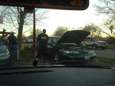 1993 Ford Taurus - A dark sedan with its hood open, displaying the license plate LFN-08M. The vehicle's body style suggests a 1995 model year.