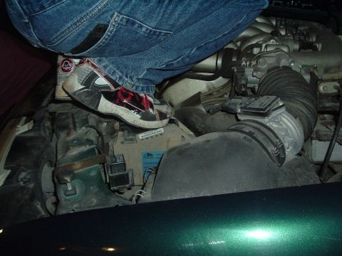 1993 Ford Taurus - Foot placed on engine parts, obscuring some of the components.