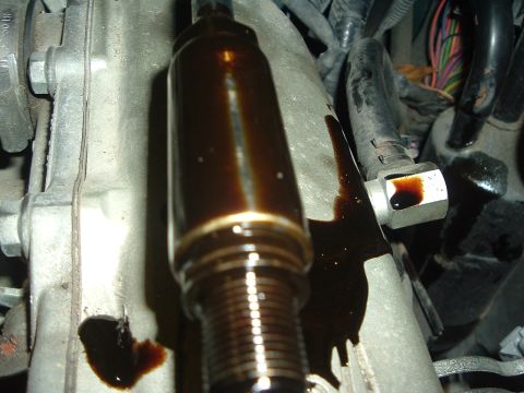 1993 Ford Taurus - This image shows a close-up of an engine part covered in dark oil, with evidence of a leak.