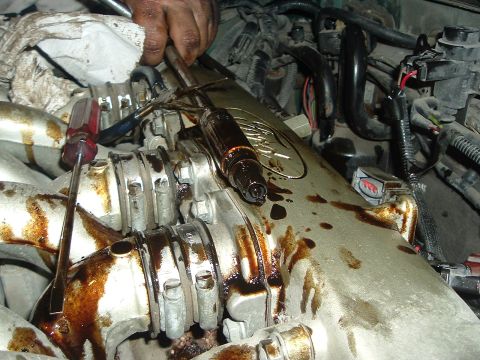 1993 Ford Taurus - Mechanic working on an engine part that is leaking oil.