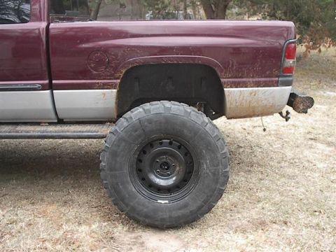 2001 Dodge 1500 - This pickup truck features a two-tone maroon and silver paint scheme and is equipped with oversized off-road tires.