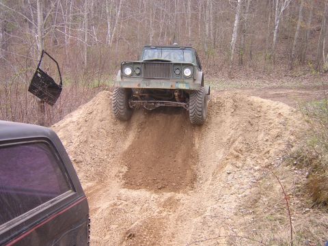 1977 Ford F-150 - A military truck navigates a steep dirt incline, while another vehicle watches from below.