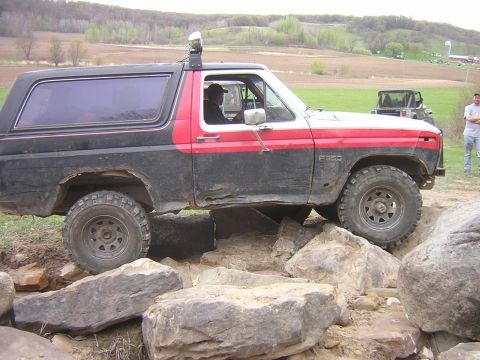 1977 Ford F-150 - A Ford Bronco navigates a rocky obstacle course with a Jeep visible in the distance.