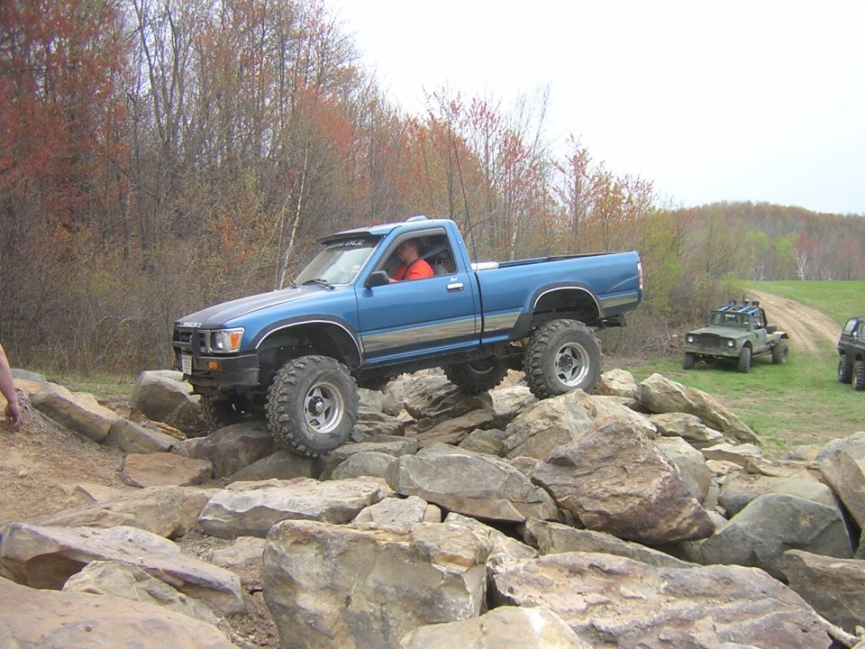 Blue pickup truck with large tires navigating a rocky trail