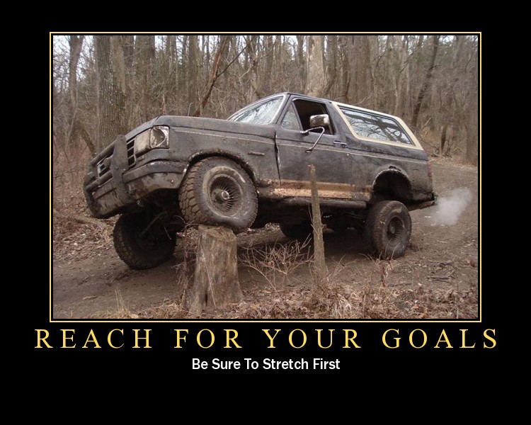 Motivational meme of muddy lifted Bronco balanced on a tree stump, 'Reach For Your Goals' text
