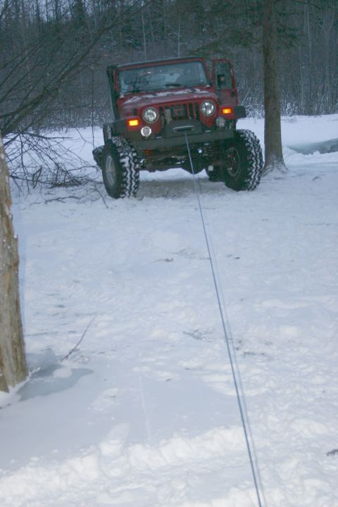 2003 Jeep TJ - A red 2003 Jeep TJ is seen in a snowy landscape, with a winch cable extending towards the viewer.