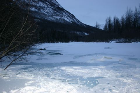 2003 Jeep TJ - Tire tracks are visible in the snow on the edge of a frozen landscape, leading towards a body of water.