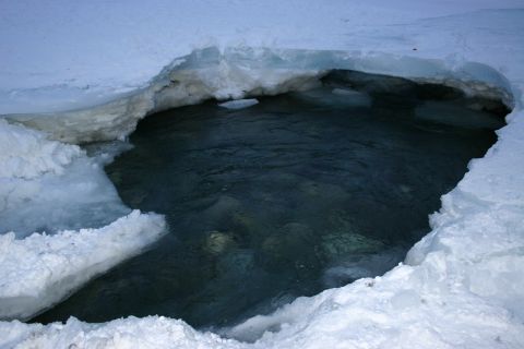 2003 Jeep TJ - A natural opening in a frozen landscape reveals dark, clear water beneath the ice.