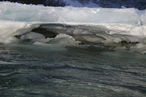 2003 Jeep TJ - A close-up view of ice formations over dark, rippling water, with icicles hanging from the ice shelf.