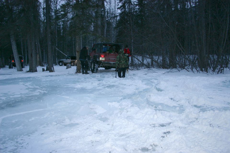 Red 2003 Jeep TJ in snowy woods with other vehicles