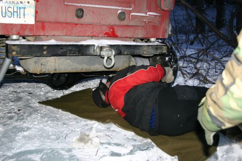2003 Jeep TJ - Person works on the rear of a red 2003 Jeep TJ in a snowy environment.