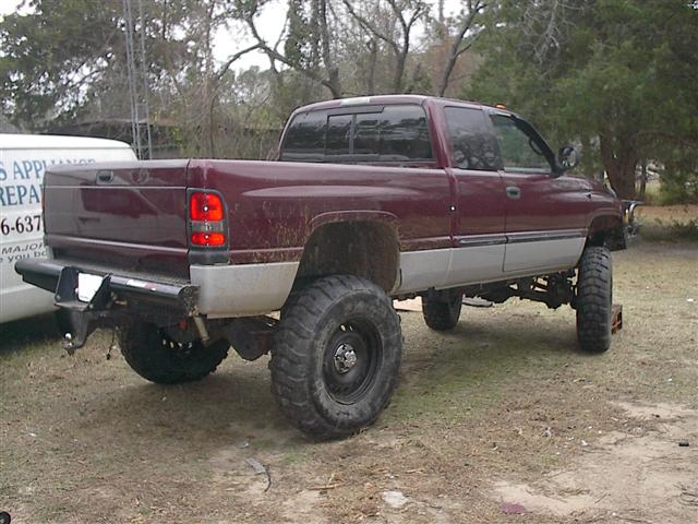 Maroon 2001 Dodge 1500 pickup truck, rear 3/4 view, lifted with large tires
