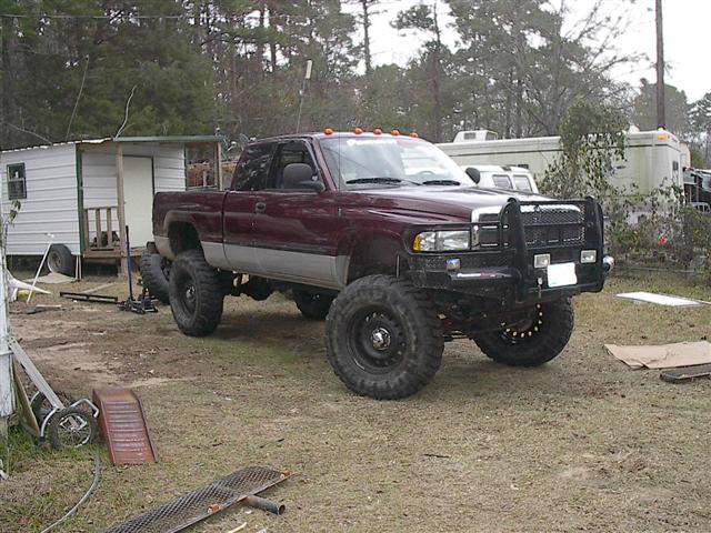 Lifted 2001 Dodge 1500 pickup truck with aftermarket bull bar and large tires parked in a yard