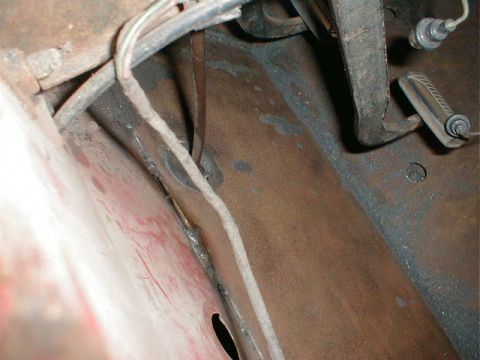 1968 Ford Bronco - Close-up view of a vehicle's undercarriage, showing rusty metal and various hoses and mechanical components.