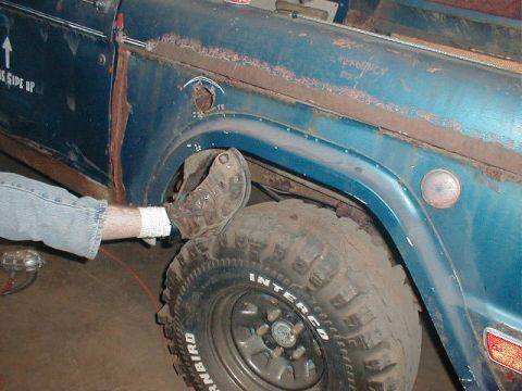 1968 Ford Bronco - Close-up of a blue SUV's fender and wheel, showing some rust and wear.