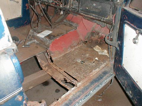 1968 Ford Bronco - Close-up view of a vehicle's interior floor, showing metal components and red seat parts.