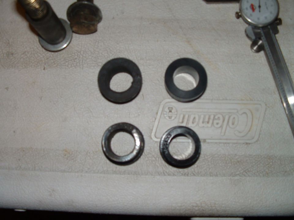 Four ring seals/bushings on a white cooler lid beside a dial caliper and bolt