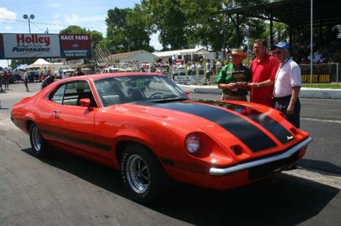 1972 Ford Ranchero - A red coupe with black racing stripes is parked on a drag strip with three men standing nearby.