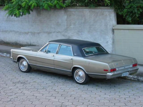 1972 Ford Ranchero - This gold sedan with a black vinyl roof is parked on a cobblestone driveway.