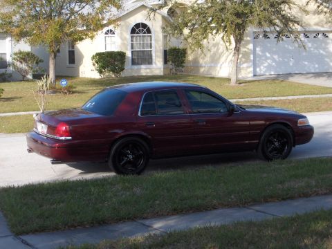 2004 Ford Crown Victoria - A maroon 2004 Ford Crown Victoria is parked in front of a house with black rims.