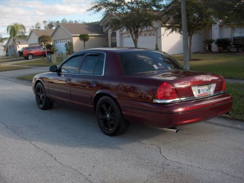 2004 Ford Crown Victoria - Maroon 2004 Ford Crown Victoria parked on a residential street with a red SUV in the background.