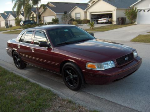 2004 Ford Crown Victoria - This maroon sedan, likely a 2003 model, is parked curbside in front of suburban homes.