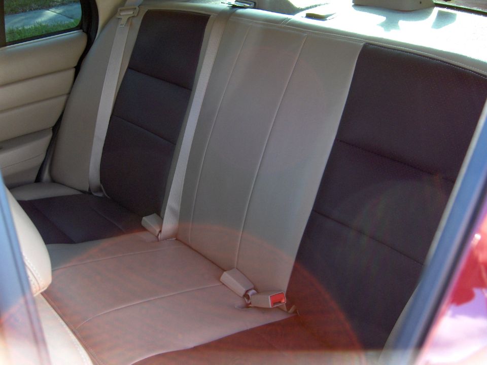 Rear bench seat with two-tone upholstery, light tan and dark brown sections, and beige seatbelts
