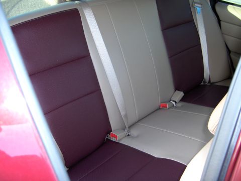 2004 Ford Crown Victoria - The interior features two-tone rear seats with tan and dark red upholstery, complete with seatbelts.