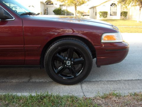 2004 Ford Crown Victoria - Close-up of a maroon sedan's front passenger side, showing the wheel and fender.