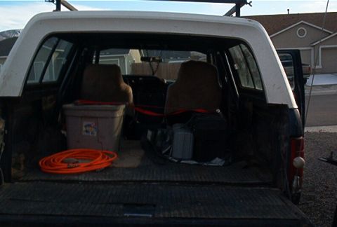 1986 Ford Bronco - The interior of a pickup truck bed and cab is shown, filled with various items and equipment.