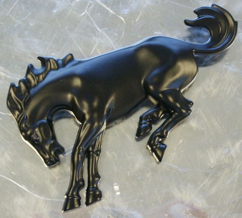 1987 Ford Bronco - This is a black horse emblem, possibly a vehicle badge, against a metallic surface.