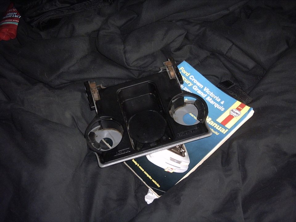 Car part with cup holders next to a Ford Crown Victoria & Mercury Grand Marquis manual