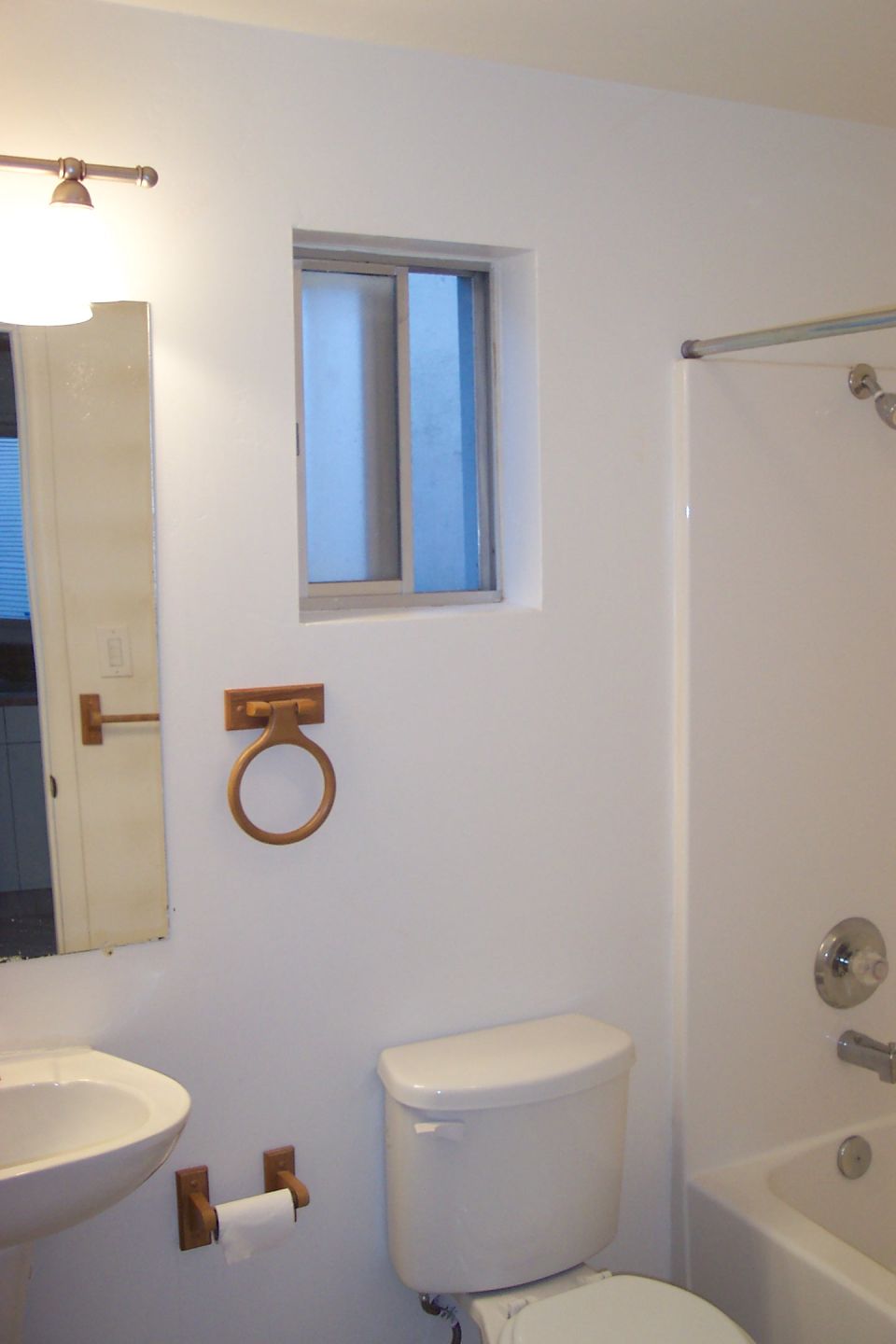 Bathroom with sink, toilet, and bathtub. A small window is above the toilet