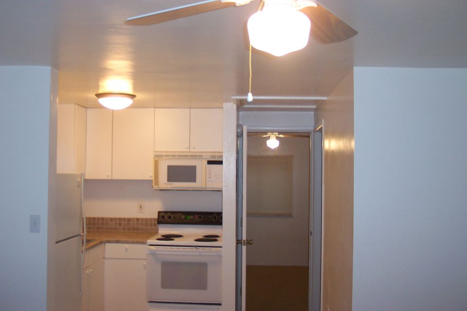 Kitchen with white cabinets, microwave, oven, and refrigerator