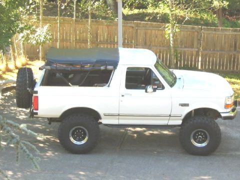 1995 Ford Bronco - This lifted 1995 Ford Bronco features a white hardtop with a dark soft top covering the rear cargo area and a spare tire mounted externally.