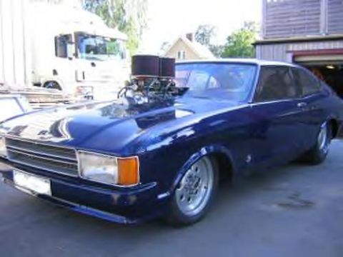 1972 Ford Ranchero - Custom blue coupe with a prominent engine modification, seen parked in front of a garage.