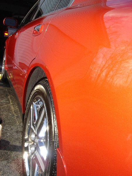 1999 Ford Taurus - Close-up of an orange sedan's rear wheel and side panel, showing water spots on the paint.