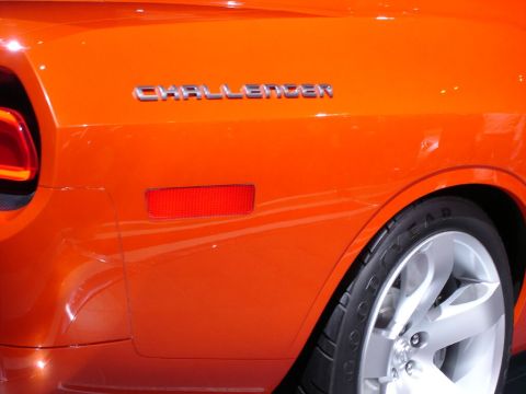 1986 Ford Bronco - Close-up of an orange car's rear quarter panel, showing the 'Challenger' badge and a red reflector.