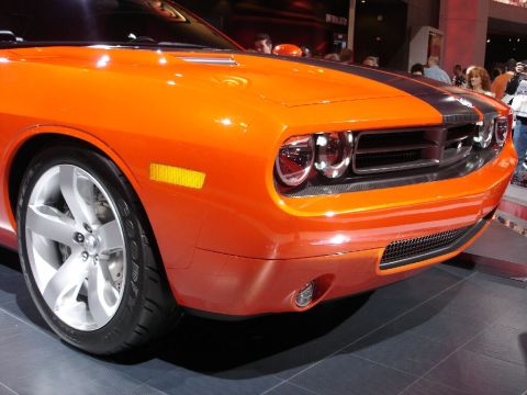 1986 Ford Bronco - Orange Dodge Challenger shown at an auto show, a distinctive front grille and headlights.