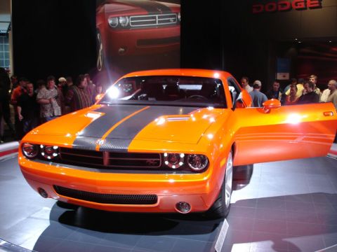 1986 Ford Bronco - An orange Dodge Challenger concept car is displayed with its driver's door open, showing off its racing stripes and distinctive headlights.