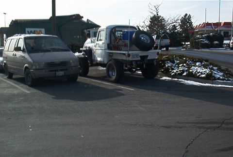 1986 Ford Bronco - Flatbed truck with spare tire and some equipment in the bed, parked in a lot.