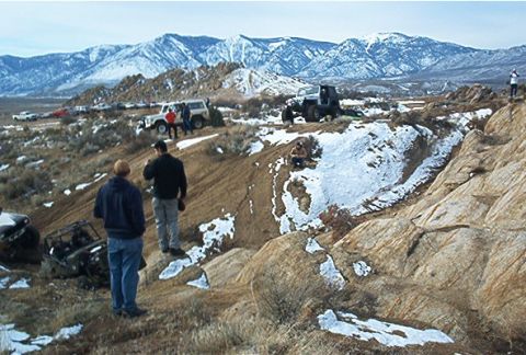 1986 Ford Bronco - Several off-road vehicles are seen in a snowy, mountainous area, with people observing the activity.