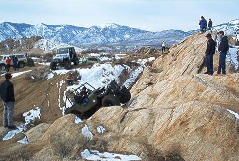 1986 Ford Bronco - Off-road enthusiasts tackle challenging terrain with multiple vehicles in a snowy, mountainous landscape.