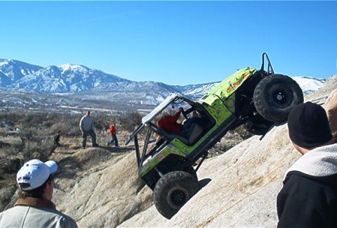 1986 Ford Bronco - An off-road jeep navigates a challenging rocky terrain, with spectators observing the difficult climb.